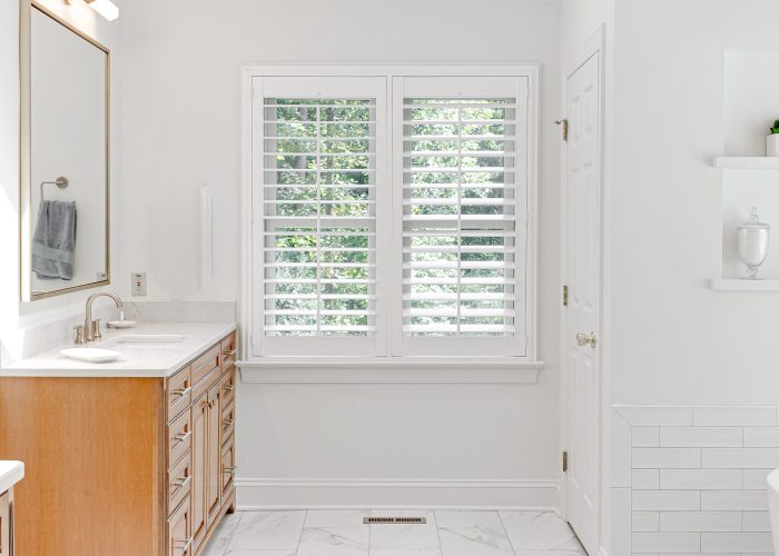 Modern luxury sunny bright primary bathroom stone countertop traditional hand towel gold mirror plantation shutter